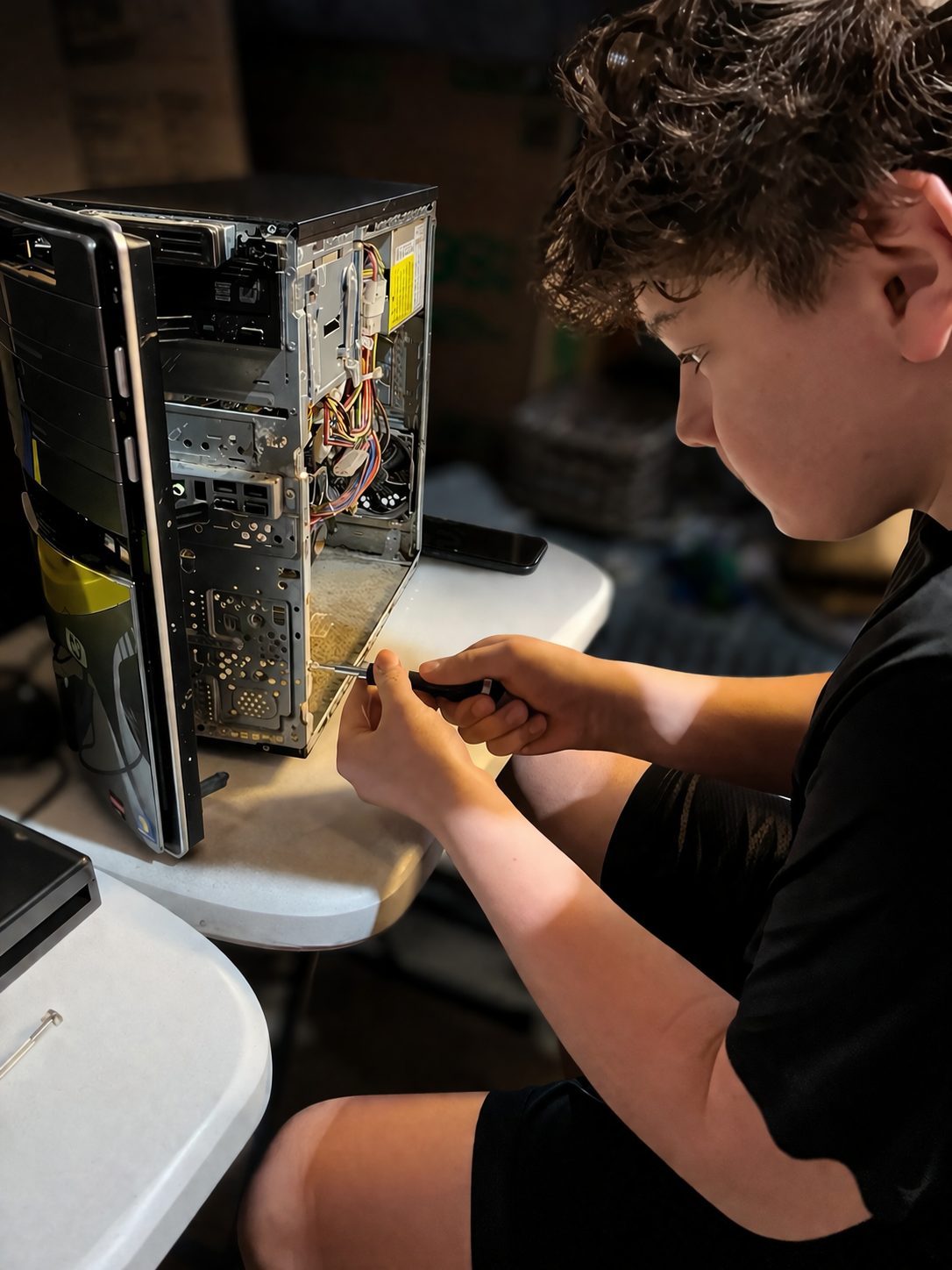 Aariyan helping with desktop computer teardown and hardware work