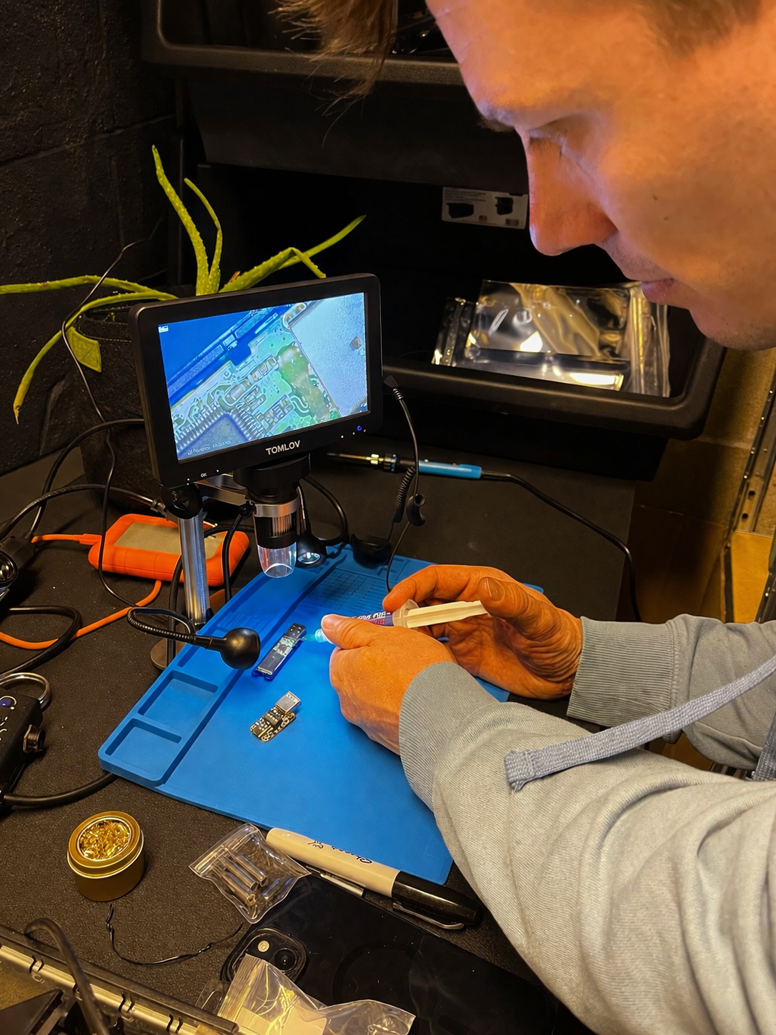 Tyler doing careful microscope work on a circuit board at the bench